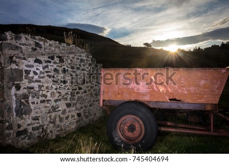 Sunrise Over The Hill With Old Farm Trailer And Stone Wall In Foreground Sunrise Over The Hill With Old Farm Trailer And Stone Wall In Foreground