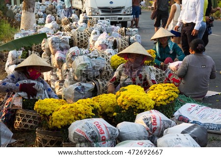 Sa Dec, Dong Thap province, Vietnam - February 07, 2015: Farmers in Vietnamese conical hat are preparing covered daisy flower pots for trading in the spring fair, the days before Tet holiday