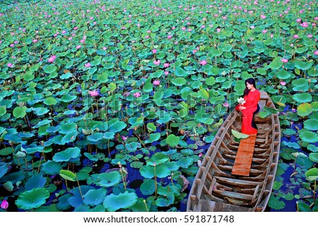Tam Da lotus lake, Ho Chi Minh city, Vietnam - February27, 2017: Vietnamese woman wearing red traditional clothing (Ao dai) sitting on sampan in lotus lake