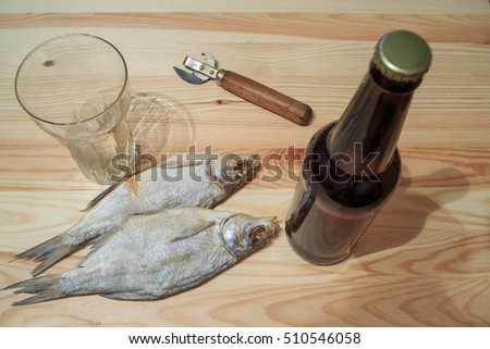 Beer bottle on a wooden table. Russian snack . Beer and dried fish. Light beer and smoked fish on the table. Peanuts, dried fish and beer.