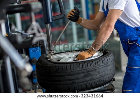 engineer balancing car wheel on balancer in workshop