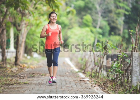 A portrait of a young asian woman doing exercise outdoor in a park, jogging