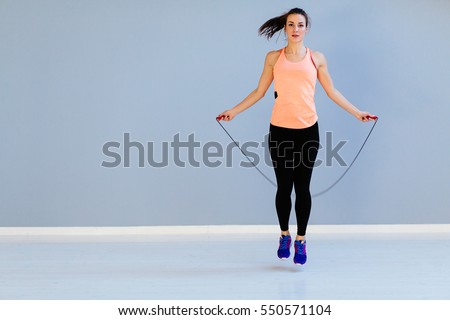 Beautiful sports girl doing exercises with jumping rope.
