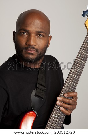 Man holding an electric 5 string bass guitar.