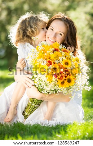 Happy child giving big bouquet of spring flowers to woman for mother`s day