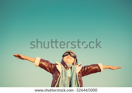 Kid pilot against autumn sky background. Happy child playing outdoors. Retro toned