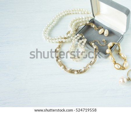 Woman's Jewelry. Vintage jewelry background. Beautiful gold and pearl necklaces, bracelets and earrings in a gift box on white wood. Flat lay, top view