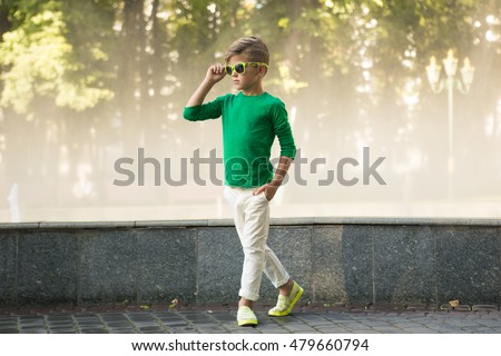 Stylish little boy in sunglasses and fashionable clothes . Children's fashion