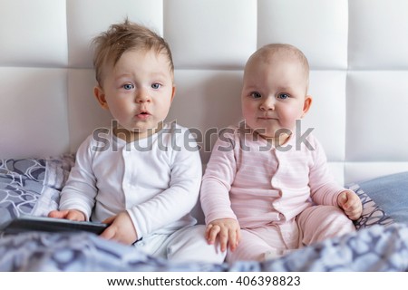 Baby boy and girl twins on parents bed in the early morning