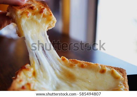 Hot toast slice with melting cheese on wood table