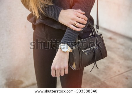 close up fashion details, young business woman holding her bag. wearing golden jewelry, and watch.