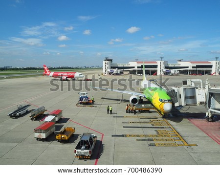 August 22, 2017 Don Mueng International Airport, Thailand : Ground staff are working at the area of the airplane of Nok Air and many trucks are parking with Air Asia in the background.