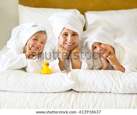 Happy mother and girls in bathrobes in room after shower