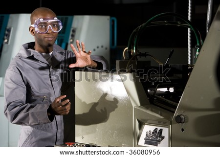 Male worker wearing protective gear beside a printing press
