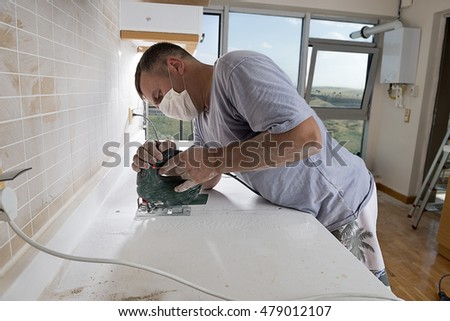 Man cutting kitchen countertop using electric jig saw with space for ...