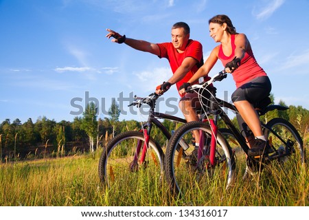 Couple of cyclists riding bicycles in meadow
