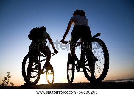 Beautiful Couple on bicycles on the brink of a rock and look afar from rock breakage