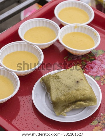 Opened Vietnamese sticky rice cake,banh chung , for the New Year holiday,Tet. containing rice, pork, mung beans wrapped in banana leaves. With bowls of Hoi An corn sweetened porridge from Cam Nam corn