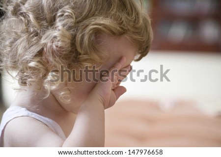 Closeup side view of unhappy baby boy rubbing eye at home