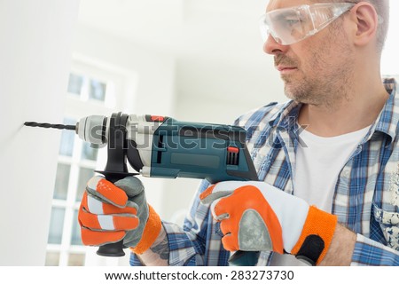 stock-photo-mid-adult-man-drilling-hole-in-wall-283273730.jpg