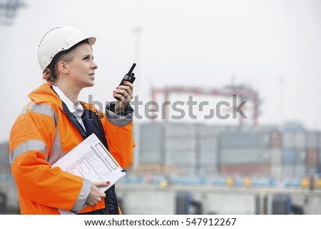 Side view of female engineer using walkie-talkie in shipping yard