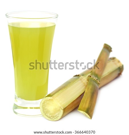 Sugarcane with juice in a glass over white background