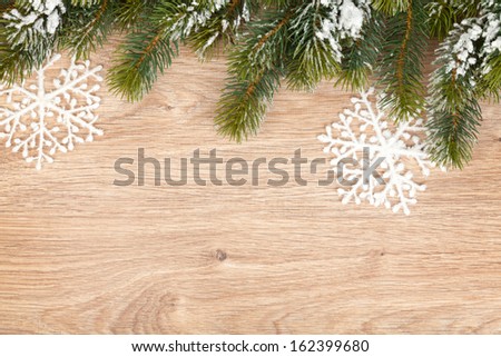 Christmas fir tree covered with snow on wooden board background