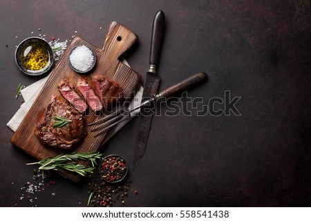 Grilled ribeye beef steak, herbs and spices. Top view with copy space for your text