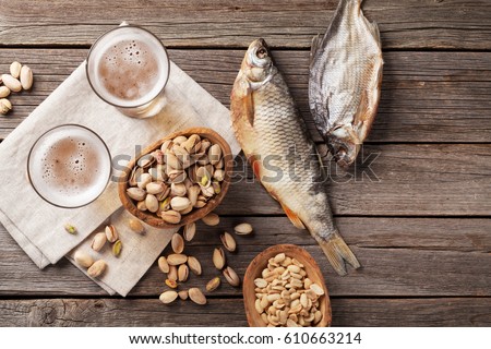 Lager beer glasses and snacks on wooden table. Nuts, chips, dry fish. Top view