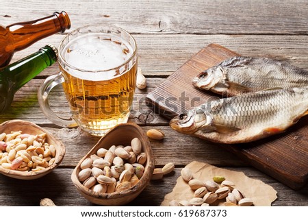 Lager beer mug and snacks on wooden table. Nuts and dry fish