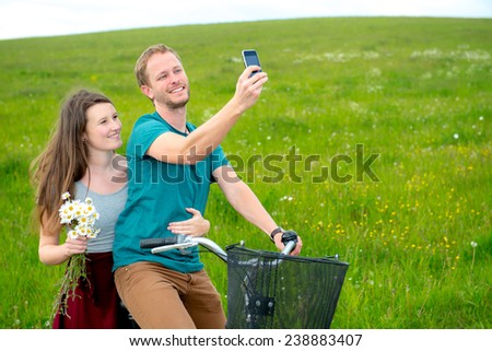 young man and woman on bicycle take a selfie