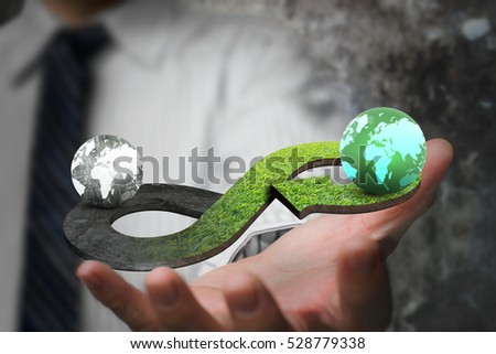 Green circular economy concept. Hand showing arrow infinity symbol with grass texture and two globes of different colors.