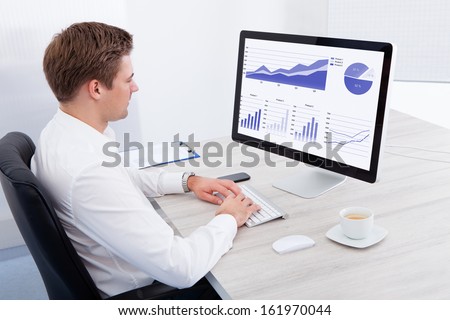 Portrait Of Young Businessman Using Computer At Desk