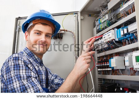 Side view of male technician examining fusebox with multimeter probe