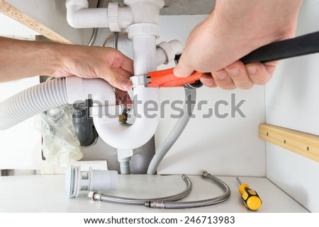 Close-up Of Male Plumber Fixing Sink In Bathroom