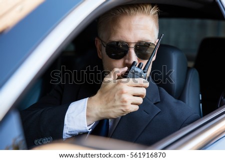 stock-photo-surveillance-man-sitting-inside-car-talking-on-walkie-talkie-561916870.jpg