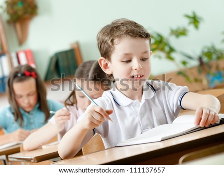 Young schoolboy does some notes with pen on the sheet of paper