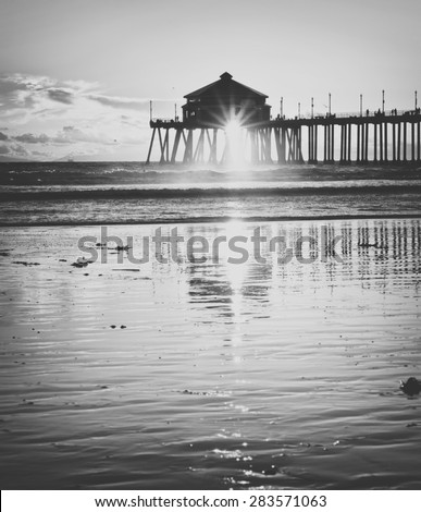 Huntington beach pier in orange county california at sunset with reflection processed in vintage black and Huntington beach pier in orange county california at sunset with reflection processed in vintage black and