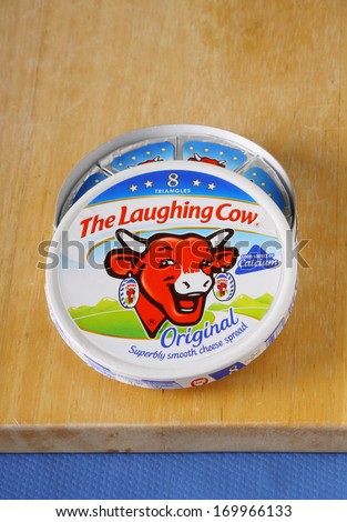 BRACKNELL, ENGLAND - JANUARY 06, 2014: An opened box of The Laughing Cow cheese spread on a chopping board. The company was founded in France in 1921.