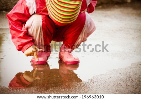 cute little girl is playing in muddy puddles