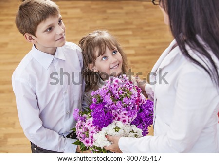 Boy and girl children give flowers as a school teacher in teacher's day