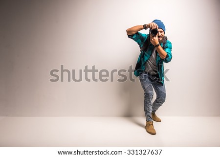 Young cheerful photographer with beard, while working in studio