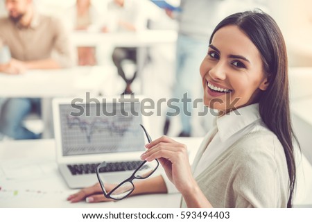 Beautiful business lady is looking at camera and smiling while working in office