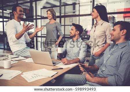 Beautiful business people are using gadgets, talking and smiling during the conference in office