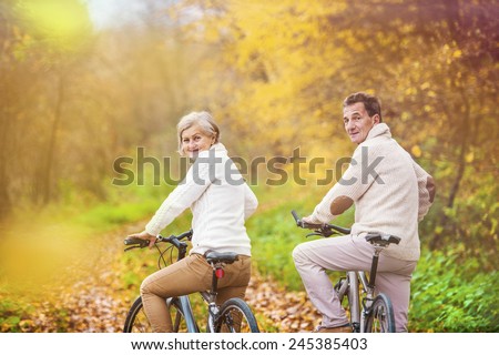 Active seniors riding bikes in autumn nature. They having romantic time outdoor.