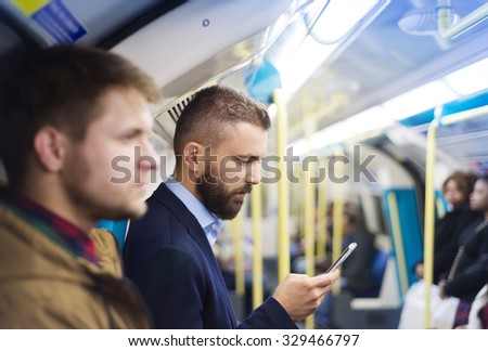 Young handsome businessman with smartphone in subway