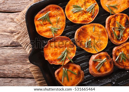 Roasted sweet potatoes with rosemary on the grill pan on the table close-up. horizontal view from above
