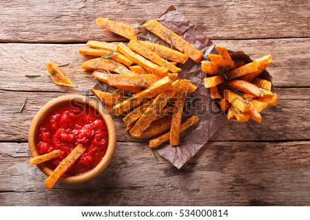 sweet potato fries with herbs and ketchup closeup on the table. Horizontal view from above