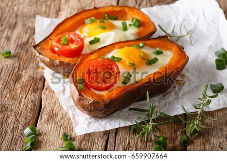 Nourishing food: stuffed sweet potato with fried egg and tomato close-up on the table. horizontal