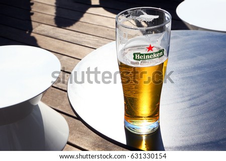 AMSTERDAM, NETHERLANDS - APR 08, 2017 : Glass with Heineken Lager Beer on outdoor bar table on sunny day. Heineken is the flagship product of Heineken International